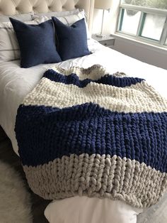 a bed with a blue and white blanket on top of it next to a window