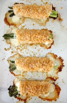 four appetizers are lined up on a white platter with broccoli and cheese