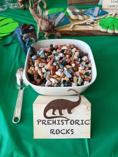 there is a bowl full of rocks and spoons next to it on the table