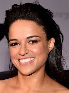 a close up of a person wearing a dress and smiling at the camera with her hair blowing in the wind