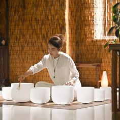 a woman standing in front of white bowls