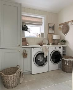 a washer and dryer sitting in a room next to each other with baskets on the floor