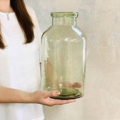 a woman holding a large glass jar with water in it's bottom and inside