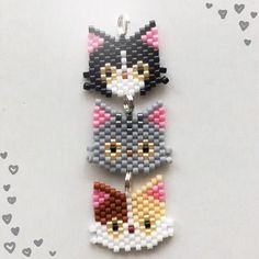 three cat keychains made out of legos on a white table with hearts