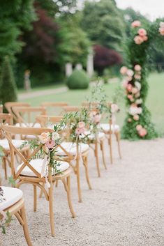 the chairs are lined up with flowers and greenery at the end of the aisle