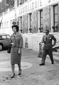 an old black and white photo of two people walking down the street