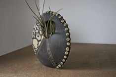 a vase with some plants in it sitting on a counter top next to a wall