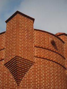 the top of a brick building with a clock on it's face and sky in the background