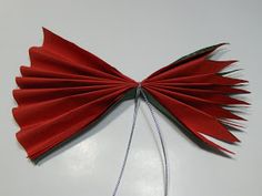 a red bow hanging on a wall with some string attached to the back of it