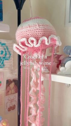 a pink crocheted jellyfish hanging from a lamp