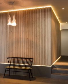 a chair sitting in front of a wall next to a stair case with lights on it