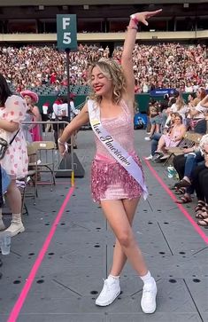 a woman in a pink dress is dancing on the stage with her arms raised up