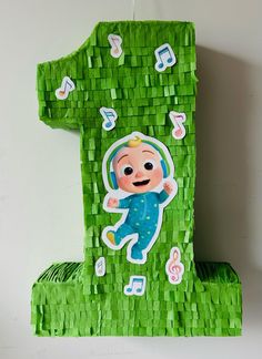 a number one made out of green paper with a baby in the center and musical notes all over it