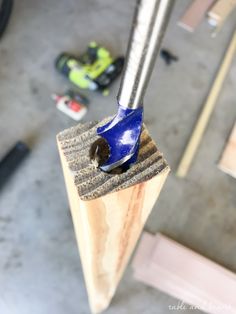 a blue bird sitting on top of a piece of wood next to a wrench