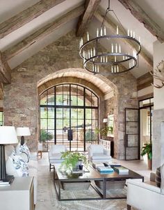 a living room filled with lots of furniture and a chandelier hanging from the ceiling