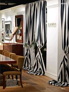 black and white curtains are hanging on the wall in front of a dining room table