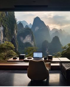 a laptop computer sitting on top of a wooden desk in front of a mountain view