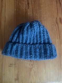 a blue knitted hat sitting on top of a wooden table