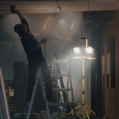 a man is standing on a ladder in the middle of a room with two lights