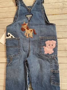 a baby's denim overalls with appliqued animals on it