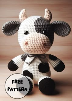 a crocheted stuffed cow sitting on top of a wooden table next to a sign that says free pattern