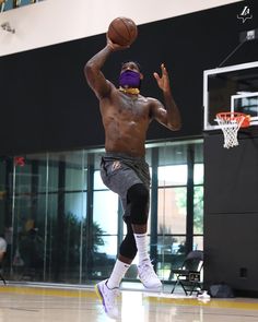 a man is playing basketball in an indoor court with the ball up to his head