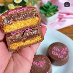 a person holding two pieces of cake in their hand with chocolate on the other side