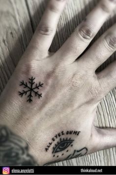 a person's hand with a snowflake tattoo on it