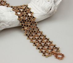 a close up of a bracelet on a white cloth with beads and chains attached to it