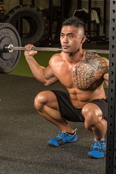 a man squats down while holding a barbell