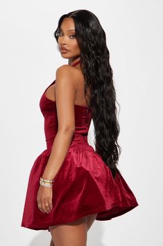 a woman in a short red dress with long hair standing and looking off to the side