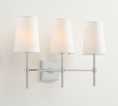 three lamps mounted on a wall next to a white light fixture with a square shaped shade