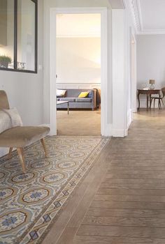 a living room with hardwood floors and white walls, along with an area rug on the floor