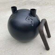 a black kettle sitting on top of a cement floor next to a barbell handle