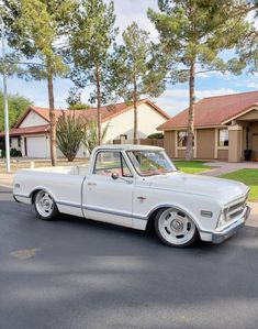 an old white truck parked in front of a house