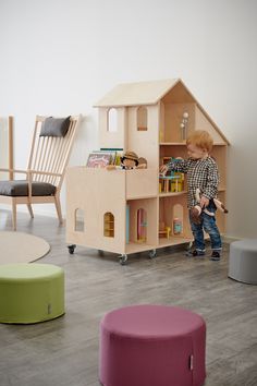 a young boy playing with toys in a playroom next to a chair and table