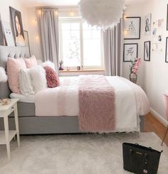 a bedroom decorated in pink and grey with pictures on the wall above the bed, along with a white rug