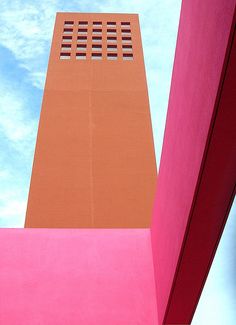 an orange and pink building with a blue sky in the backgroung area