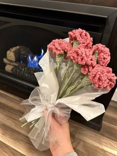 a person holding a bunch of flowers in front of a fire place