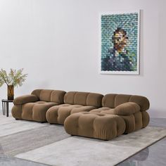 a large sectional couch sitting on top of a rug in a living room next to a painting