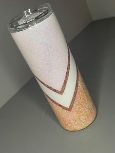 a white and pink cup sitting on top of a gray table next to a wall