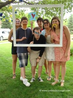 a group of young people posing for a photo in front of a frame with balloons