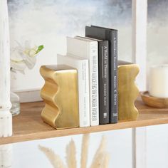 two books are sitting on a shelf next to some candles and flowers in vases