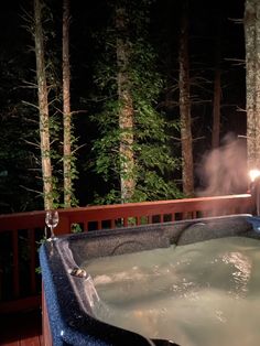 a hot tub on a deck with trees in the background at night, lit by a candle