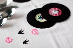 there are some black and pink vinyl records on the table with spoons next to it