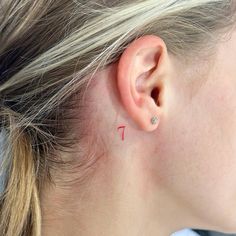 a woman's ear has a tiny red arrow tattoo on it