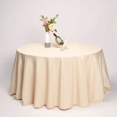 a vase with flowers on top of a white round table cloth covered by a satin tablecloth