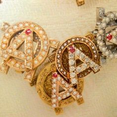 three brooches with pearls on them sitting on a white tablecloth next to each other