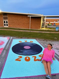 a woman sitting on the ground in front of a painted area with a record player