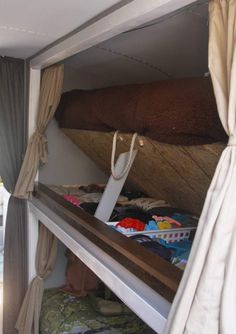 there is a bunk bed in the back of a truck with clothes on it and a bag hanging from the top